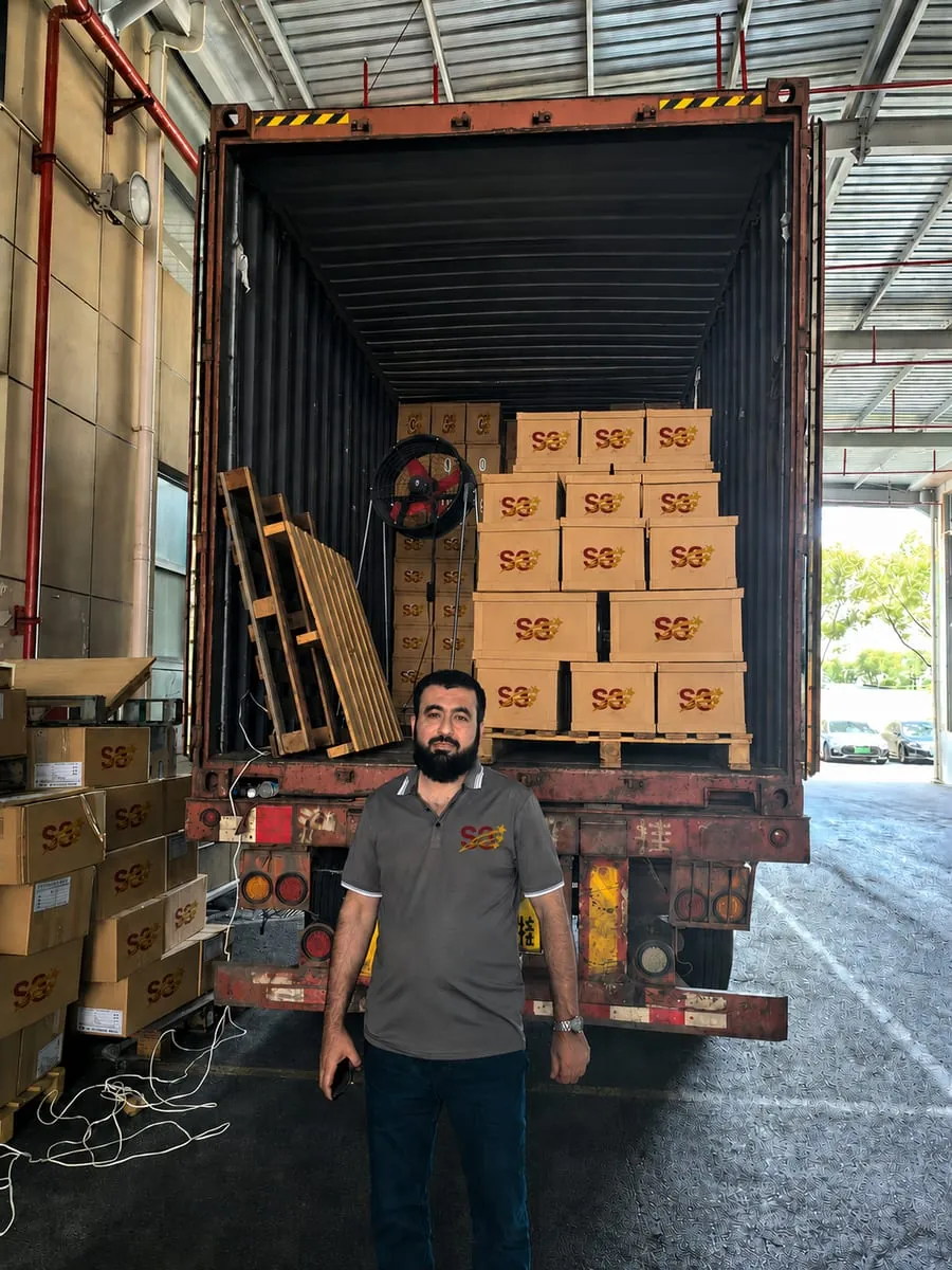 A member of the S3 team in front of a container being loaded with S3-branded cartons