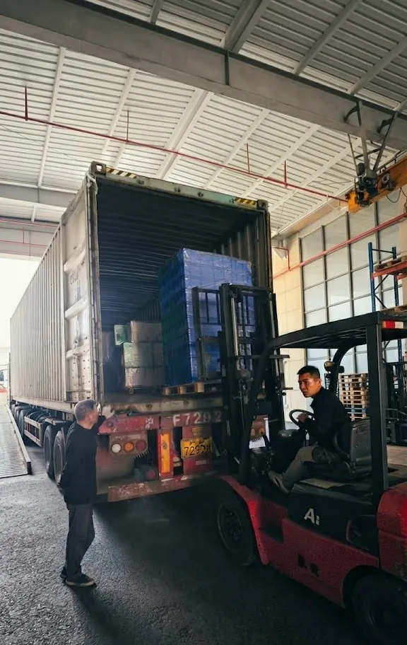 A forklift loading pallets of stock into a shipping container