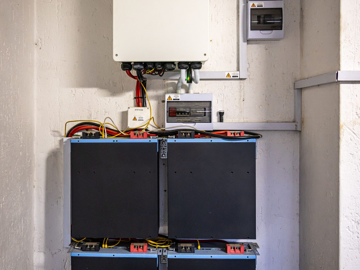 Wall-mounted hybrid inverter above a stacked lithium battery bank