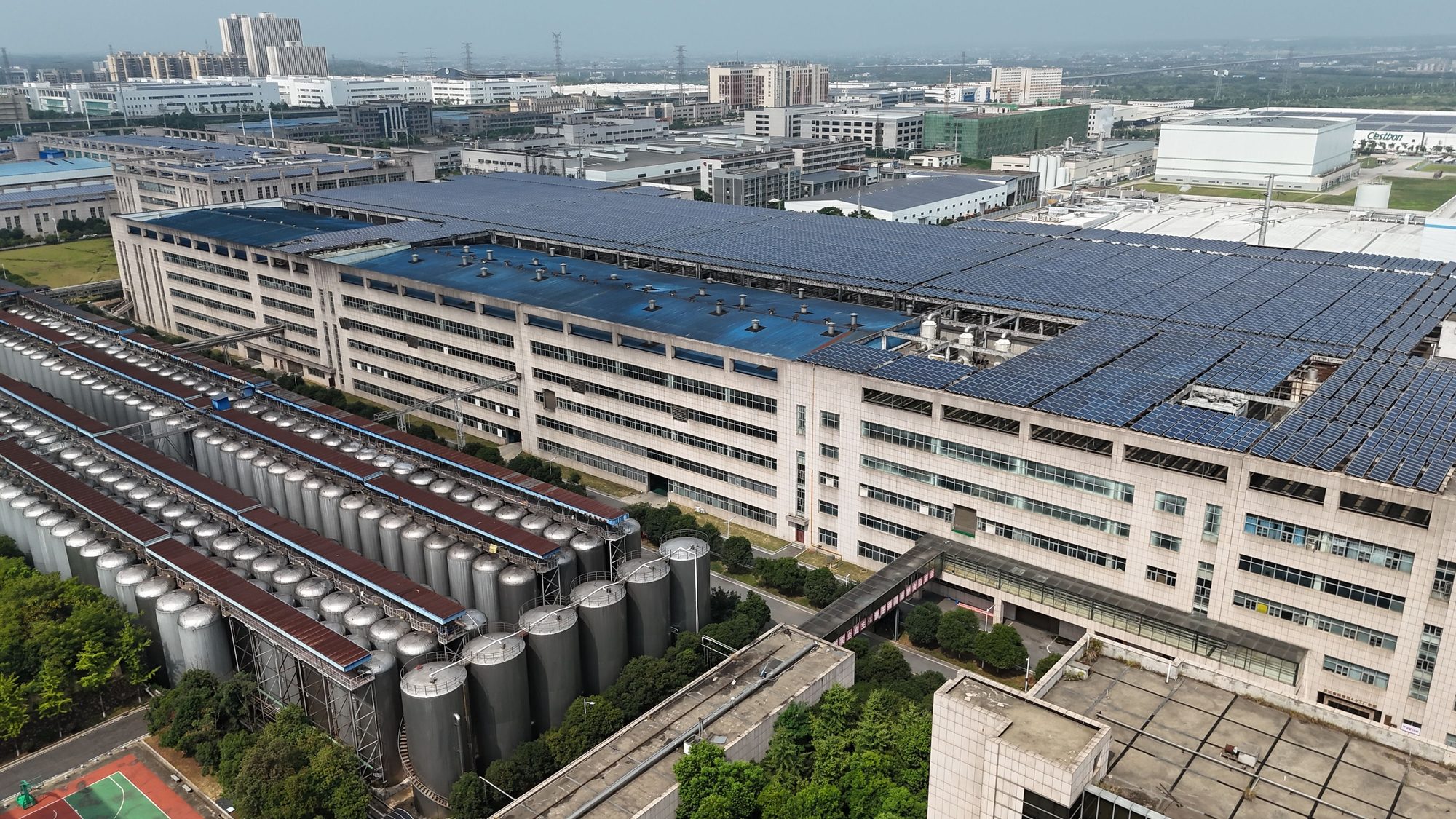 Aerial view of a large factory with a full rooftop solar installation