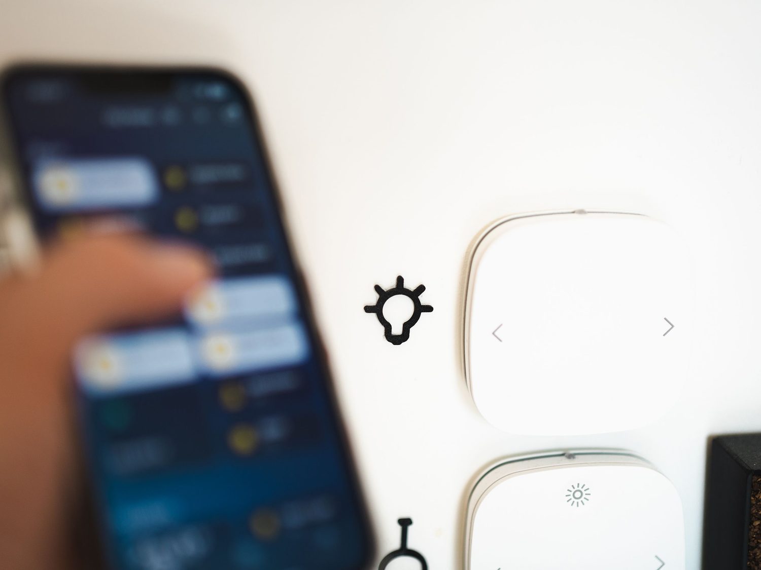Person checking a home energy app on their phone beside wall controls